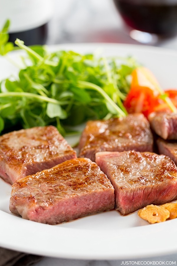 Wagyu Kobe Beef and salad on a white plate.