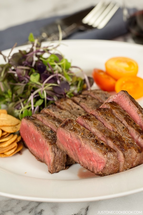 American Kobe Beef steak and salad on a plate.