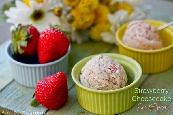 Strawberry Cheesecake Ice Cream in cups and strawberries on a wooden table.