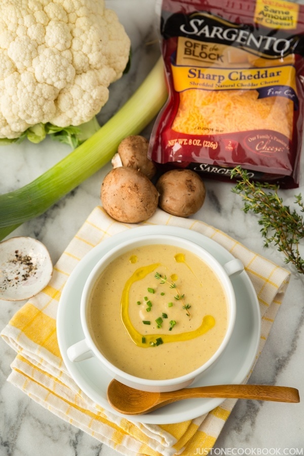Creamy Roasted Cauliflower Soup in a bowl and ingredients on a table.