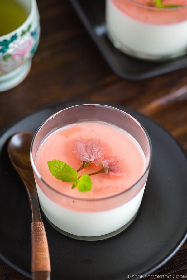 Cherry Blossom Milk Pudding in a glass cup served with green tea.
