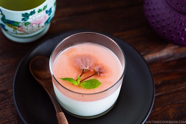 Cherry Blossom Milk Pudding in a glass cup served with green tea.