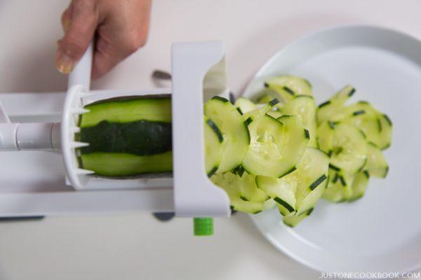 Spiralizer and cucumber on a table.