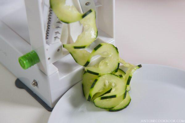 Spiralizer and cucumber on a table.