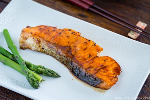 Teriyaki Salmon and steamed asparagus on the white plate.