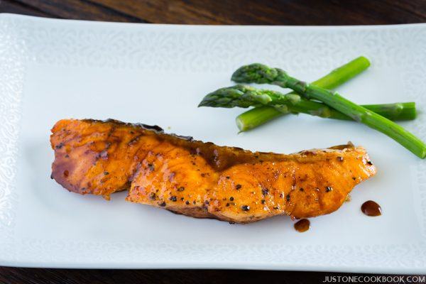 Teriyaki Salmon and steamed asparagus on the white plate.