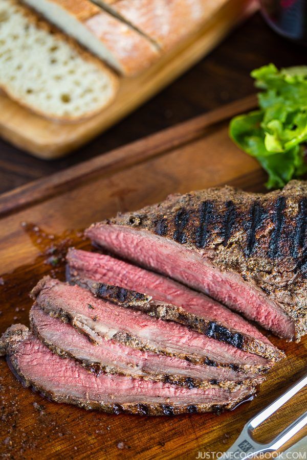 Santa Maria Tri-Tip on a cutting board and loaf of bread on the wooden table.