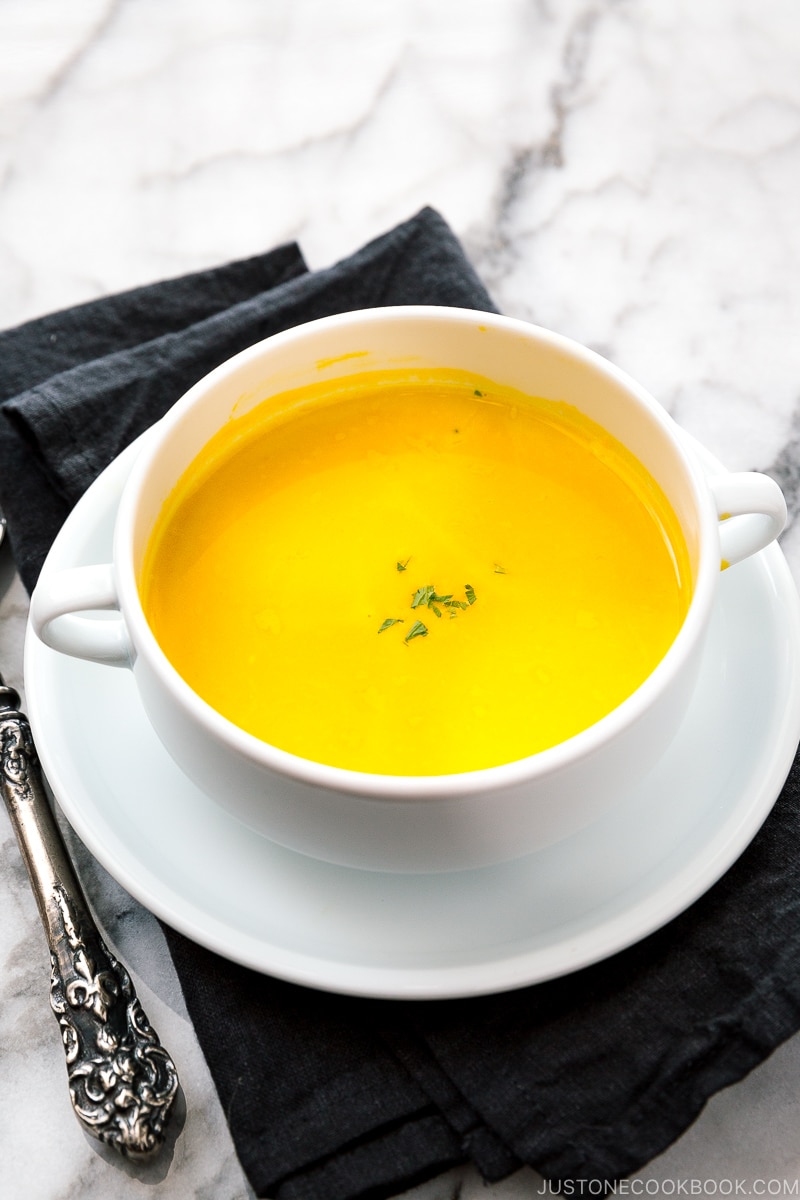 bowl with kabocha soup on top of black napkin and marble table