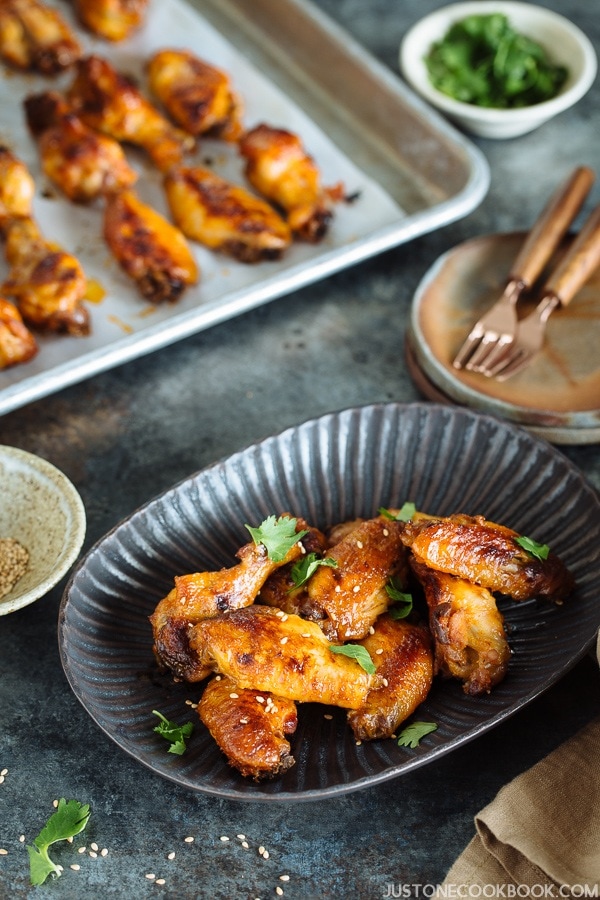 Slow Cooker Sriracha Chili Chicken Wings on a plate and a baking pan.