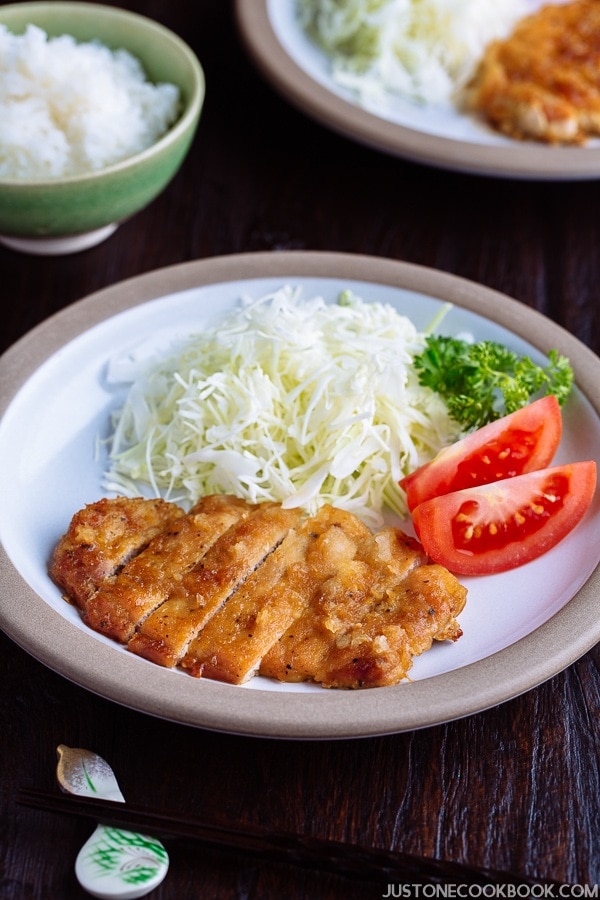 Tonteki, Japanese Pork Steak with cabbage and tomato salad on a plate.