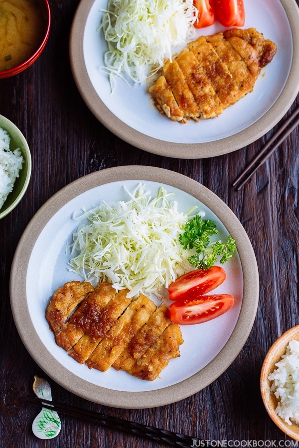 Tonteki, Japanese Pork Steak with cabbage and tomato salad on a plate.