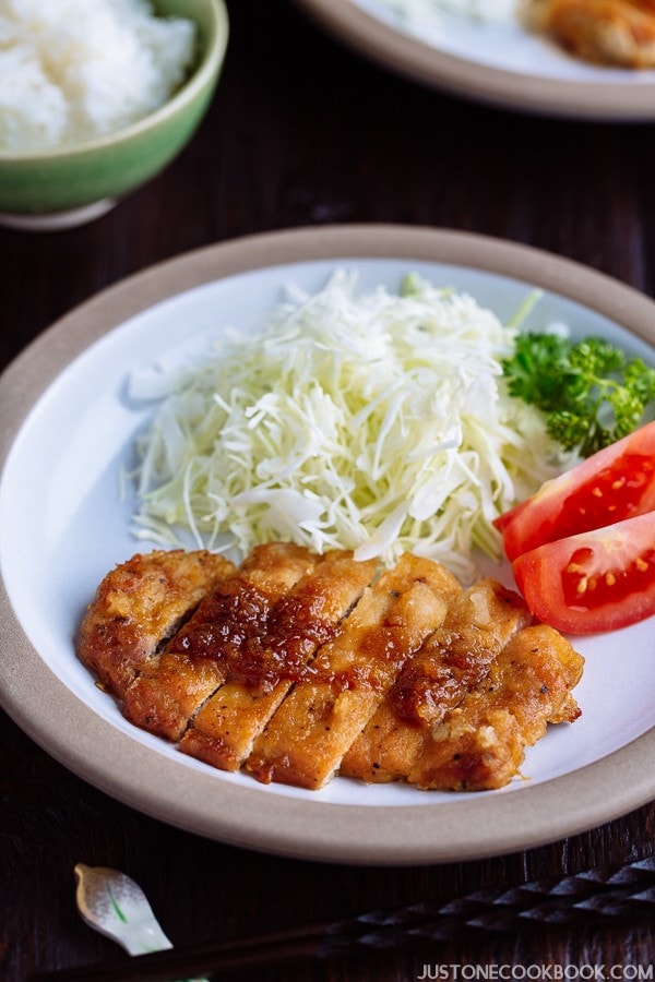 Tonteki, Japanese Pork Steak with cabbage and tomato salad on a plate.