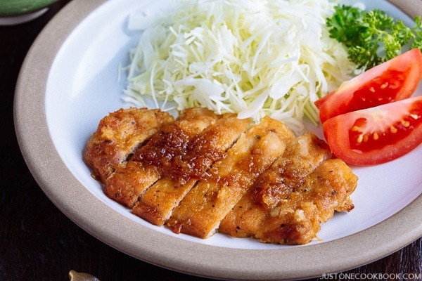 Tonteki, Japanese Pork Steak with cabbage and tomato salad on a plate.