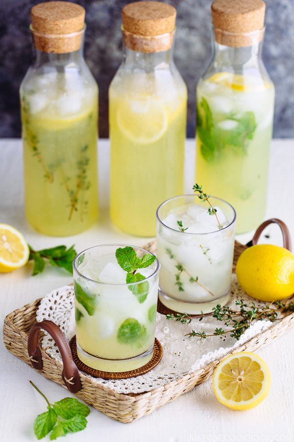 Homemade Lemonade in bottles and two glass of ice with lemonade on table.
