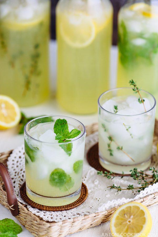 Homemade Lemonade in bottles and two glass of ice with lemonade on table.