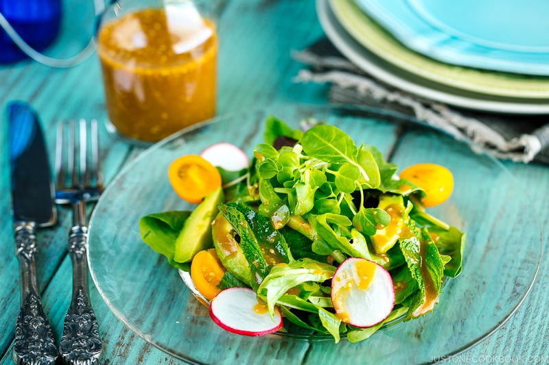 spring mix salad featuring avocado, heirloom tomatoes, radishes on a plate