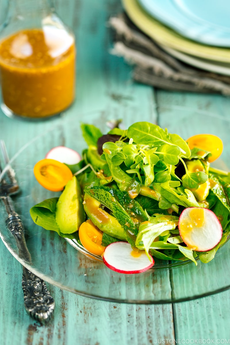 spring mix salad featuring avocado, heirloom tomatoes, radishes on a plate