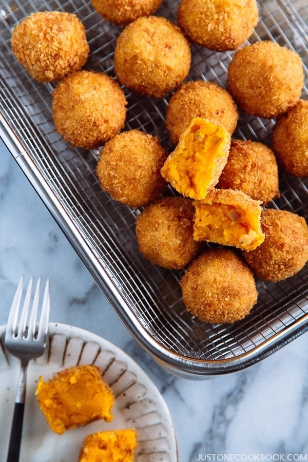 A wire rack containing small ball shape Japanese pumpkin croquettes.