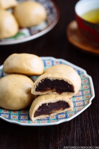 A colorful Japanese plate containing manju filled with red bean paste.