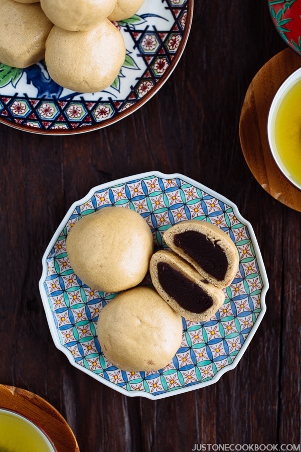 A colorful Japanese plate containing manju filled with red bean paste.