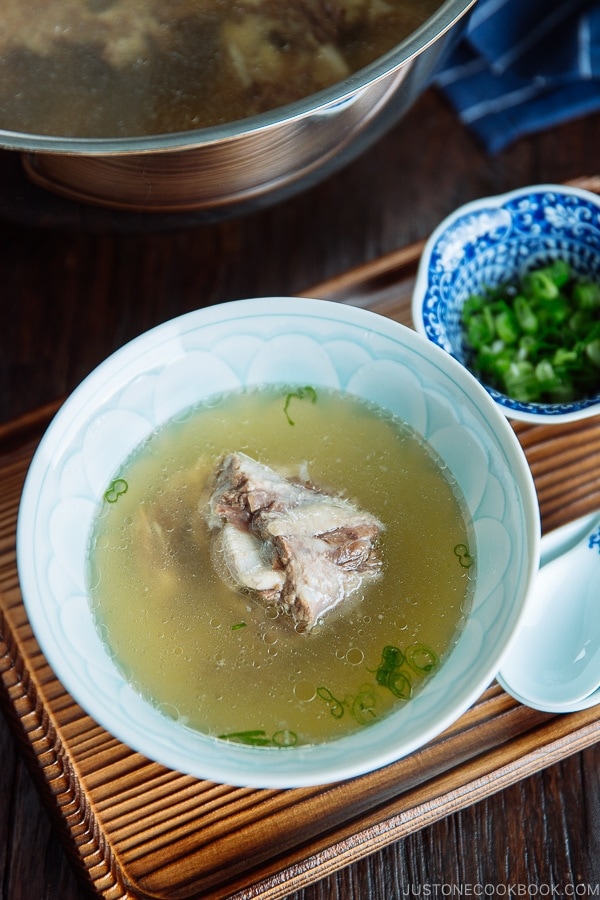 Piping hot oxtail broth in a Japanese bowl topped with green onions.