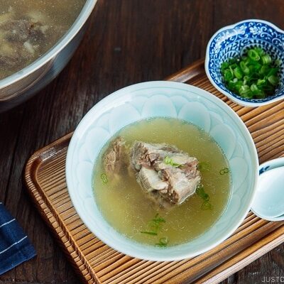 Piping hot oxtail broth in a Japanese bowl topped with green onions.