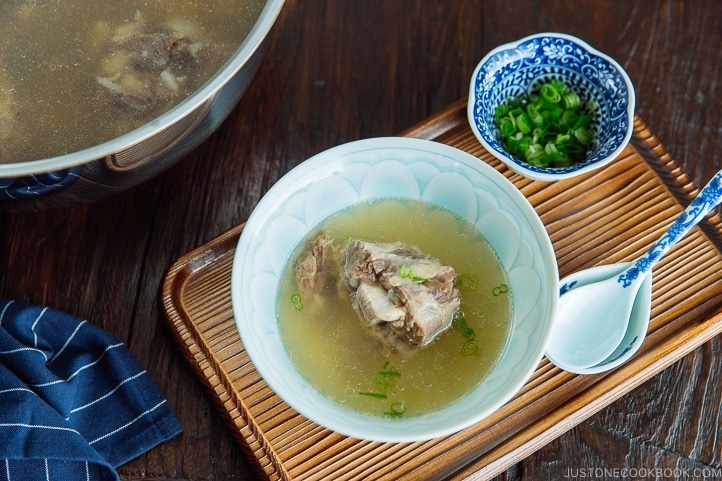 Piping hot oxtail broth in a Japanese bowl topped with green onions.