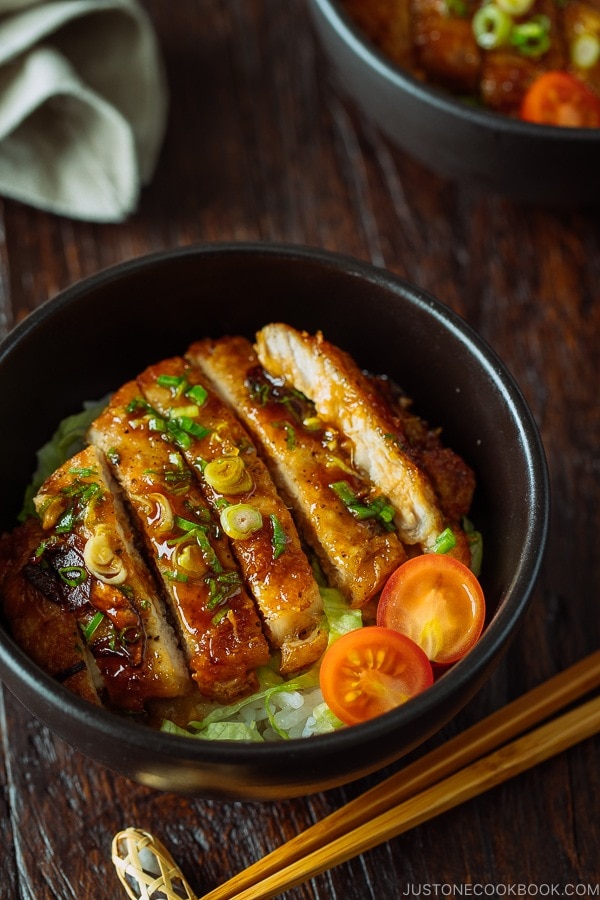 A black bowl containing Teriyaki Pork over steamed rice drizzled with homemade teriyaki glaze.