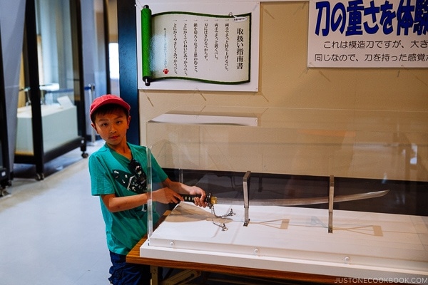 boy lifting sword on display inside Hiroshima Castle | JustOneCookbook.com