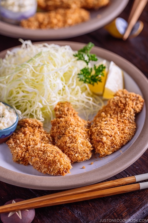Kaki Fry (Japanese Panko Fried Oysters) served with tartar sauce and shredded cabbage on the white plate.