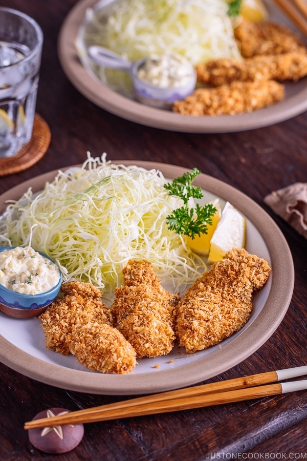 Japanese Fried Oysters (Kaki Fry) served with tartar sauce and shredded cabbage on the white plate.