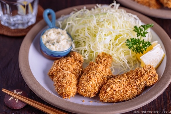 Japanese Fried Oysters (Kaki Fry) served with tartar sauce and shredded cabbage on the white plate.