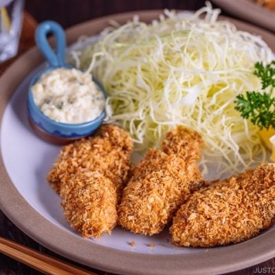 Kaki Fry (Japanese Panko Fried Oysters) served with tartar sauce and shredded cabbage on the white plate.