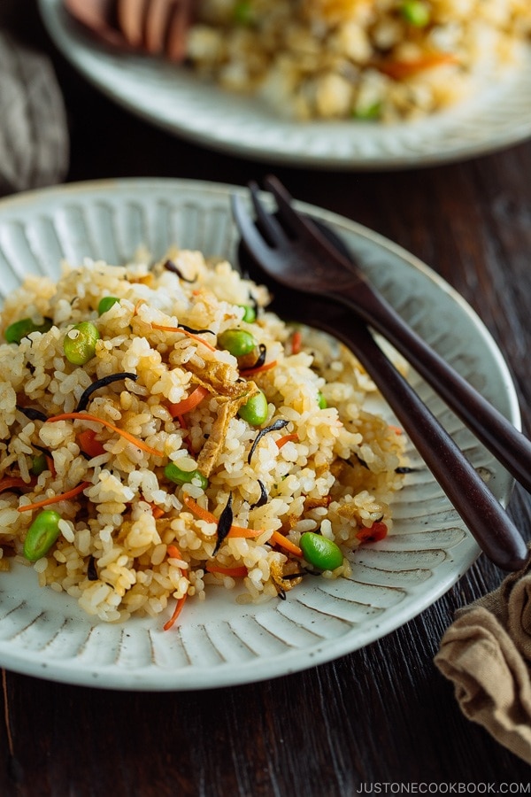 Japanese Fried Rice with Edamame, Tofu and Hijiki Seaweed on a white plate served with wooden utensils.