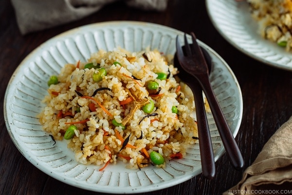 Japanese Fried Rice with Edamame, Tofu and Hijiki Seaweed on a white plate served with wooden utensils.
