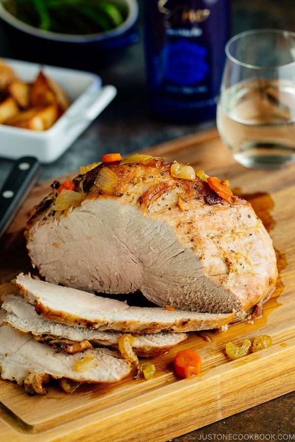 Japanese Pork Roast being sliced on a wooden cutting board.