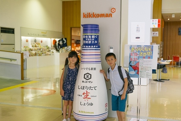 children next to a giant soy sauce bottle at Kikkoman Factory in Noda Japan | Kikkoman Factory Tour - justonecookbook.com