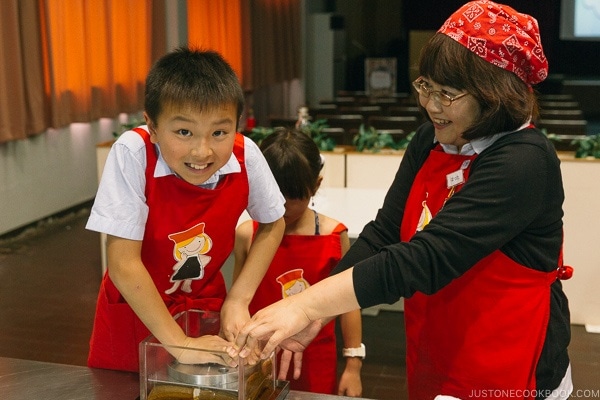 children pressing weight on fabric soaked in soy sauce at Kikkoman Factory in Noda Japan | justonecookbook.com