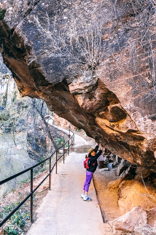 child pretending to hold up rock on Riverside Walk - Zion National Park Travel Guide | justonecookbook.com