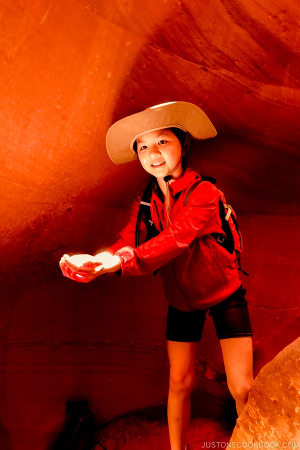 Niño sosteniendo un rayo de luz junto a una formación de roca de arena - Excursión fotográfica al Cañón del Antílope inferior | justonecookbook.com