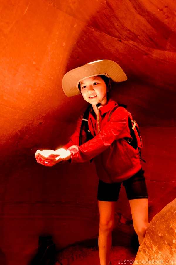 Kind hält einen Lichtstrahl neben Sandsteinformation - Lower Antelope Canyon Photo Tour | justonecookbook.com