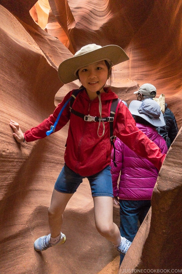 child supporting self between 2 sand rock walls - Lower Antelope Canyon Photo Tour | justonecookbook.com
