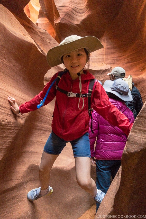 niño sosteniéndose entre 2 paredes de roca de arena - Excursión fotográfica por el Bajo Antílope Canyon | justonecookbook.com