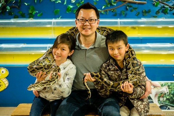 A man with two children with a snake wrapped around them