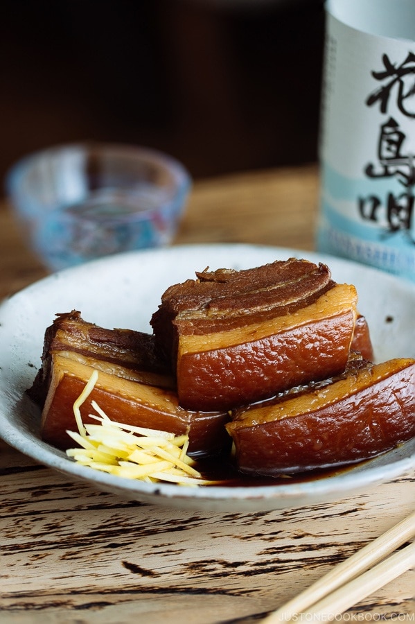 A white plate containing 3 slices of Rafute (Okinawan Braised Pork Belly) garnished with julienned ginger.