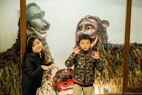 children in front of shisa figures at Ryukyu Mura Okinawa | justonecookbook.com