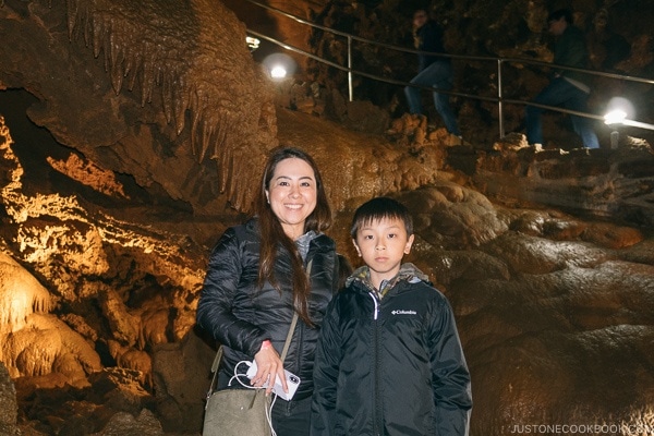 Nami and child standing next to stalactites formation inside cave - Lake Shasta Caverns Travel Guide | justonecookbook.com