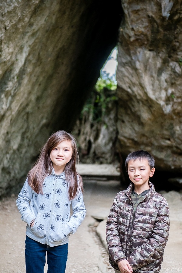 children in front of the large stone structure at Seifa-utaki 斎場御嶽 - Okinawa Travel Guide | justonecookbook.com
