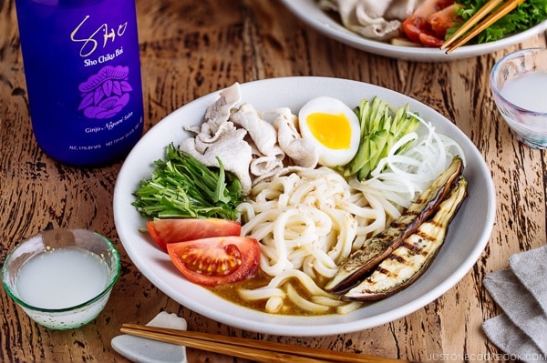 Cold Curry Udon served with thinly sliced pork, grilled eggplant, boiled egg, cucumber, and tomatoes in a chilled curry sauce.