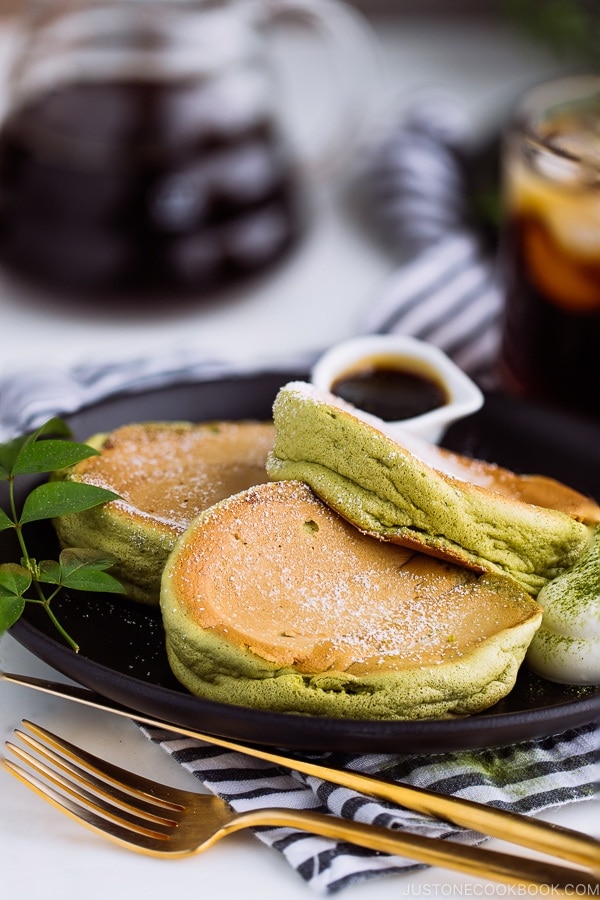 Matcha Souffle Pancakes topped with powder sugar and fresh whipped cream.